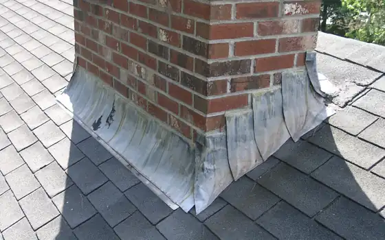 Example photo: Metal flashing at the base of a brick chimney on an asphalt shingle roof