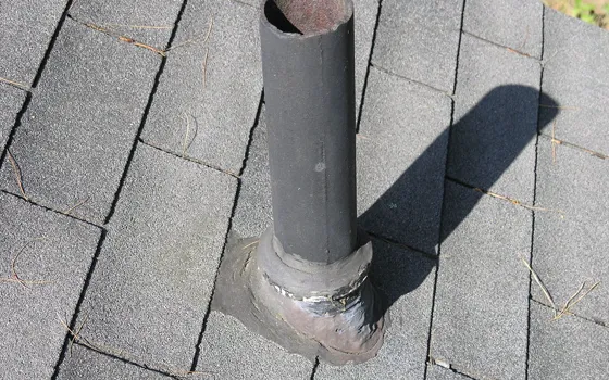 Example photo: Plumbing vent pipe with a metal flashing collar on an asphalt shingle roof